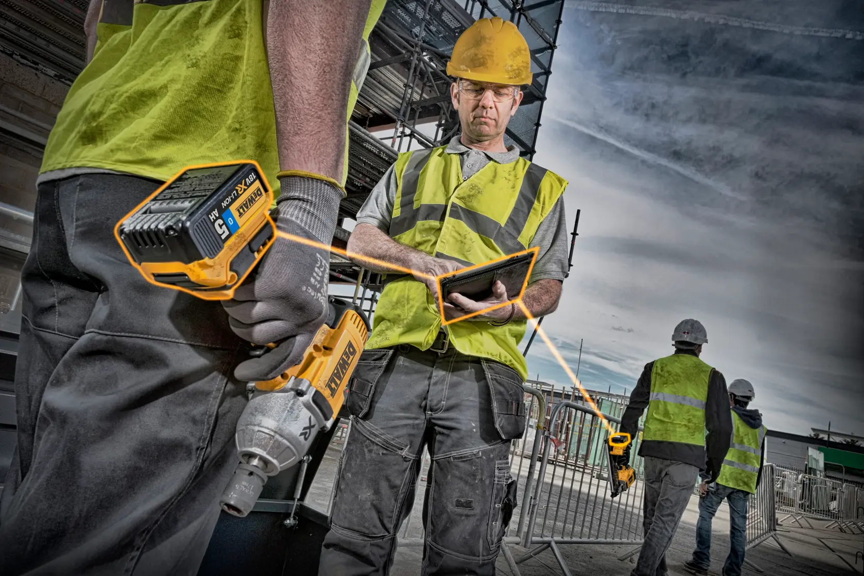 Construction workers wearing safety vests and helmets are seen at a work site. One worker is holding a DEWALT cordless power tool and another is using a tablet. Scaffolding and fencing are visible in the background.