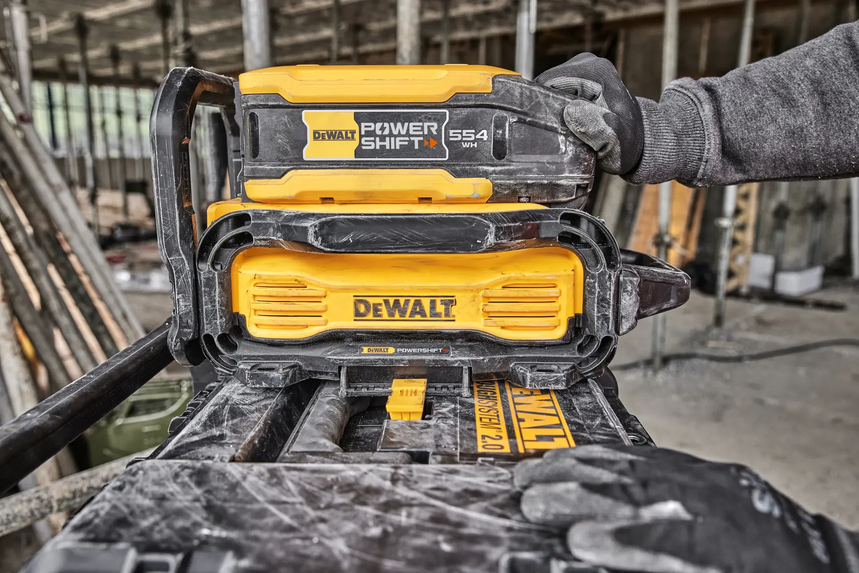 DEWALT PowerShift battery system being used on a construction site, worker's gloved hands are visible.