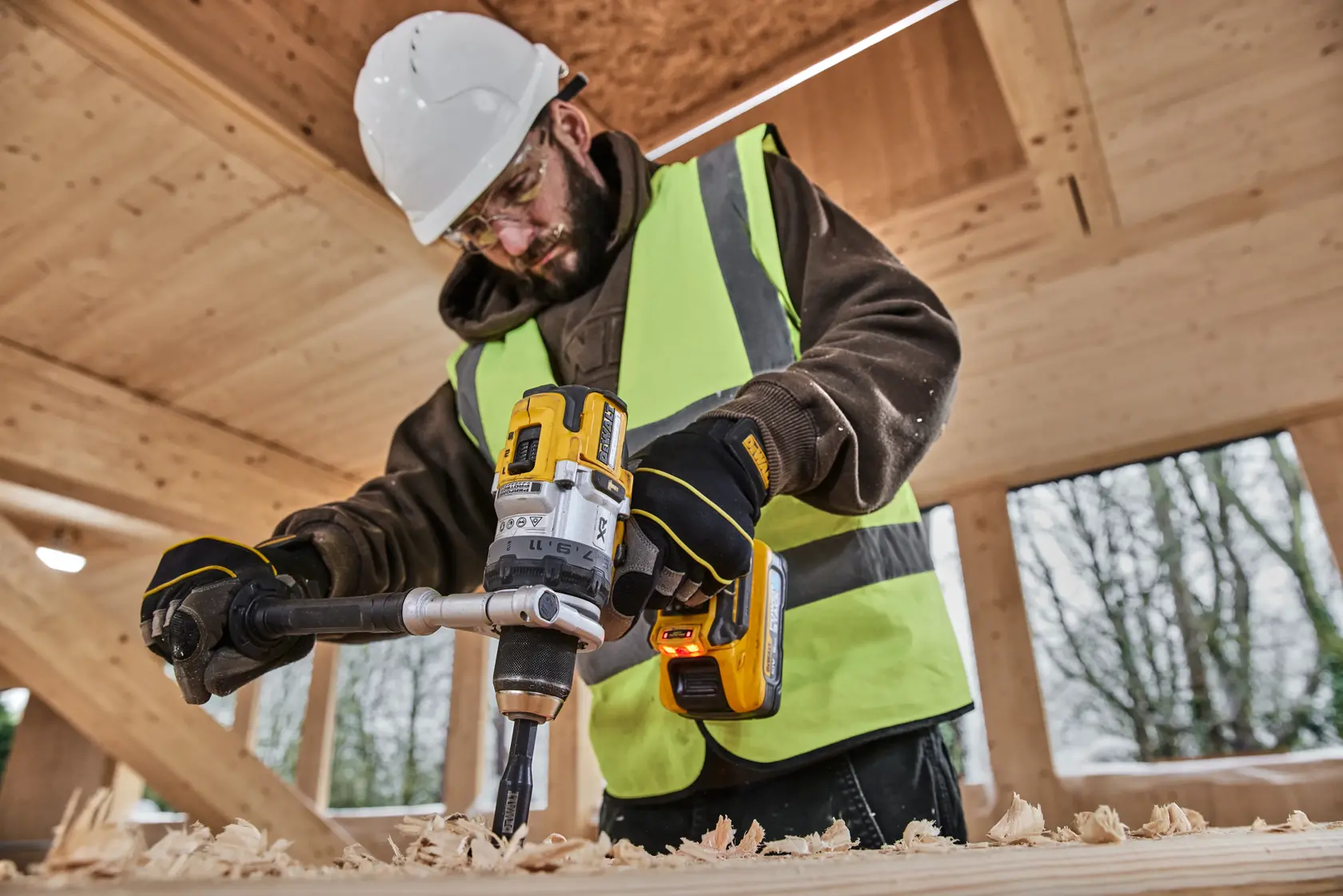 DEWALT DCD1007NT, DCZ607X2-XE drill used in construction setting, person in safety gear working with wood.