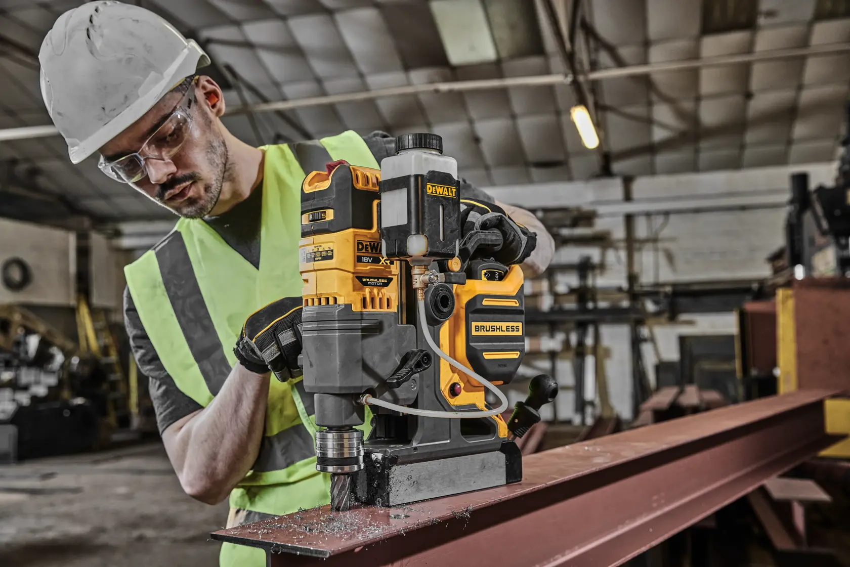 DEWALT DCD1623N brushless drill in use on metal beam in industrial workshop, operated by person in safety gear.
