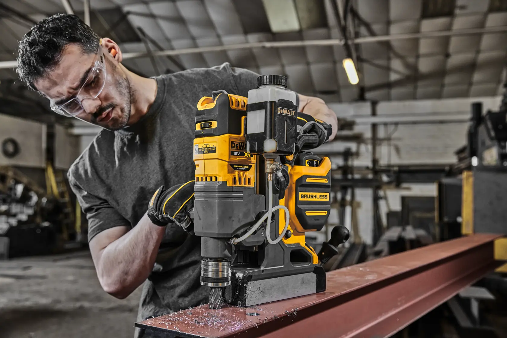 DEWALT DCD1623N brushless drill used on steel beam in workshop by person with face obscured.