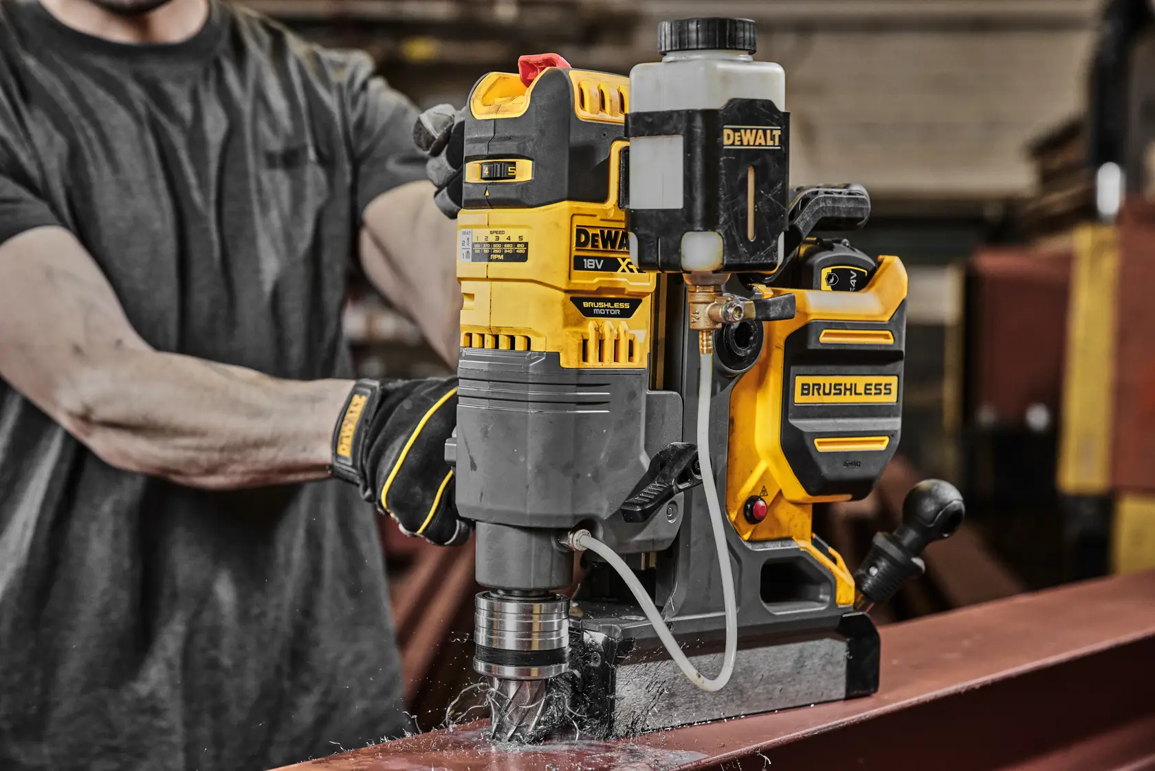DEWALT brushless magnetic drill is used to bore a hole in a steel beam in an industrial workshop setting.