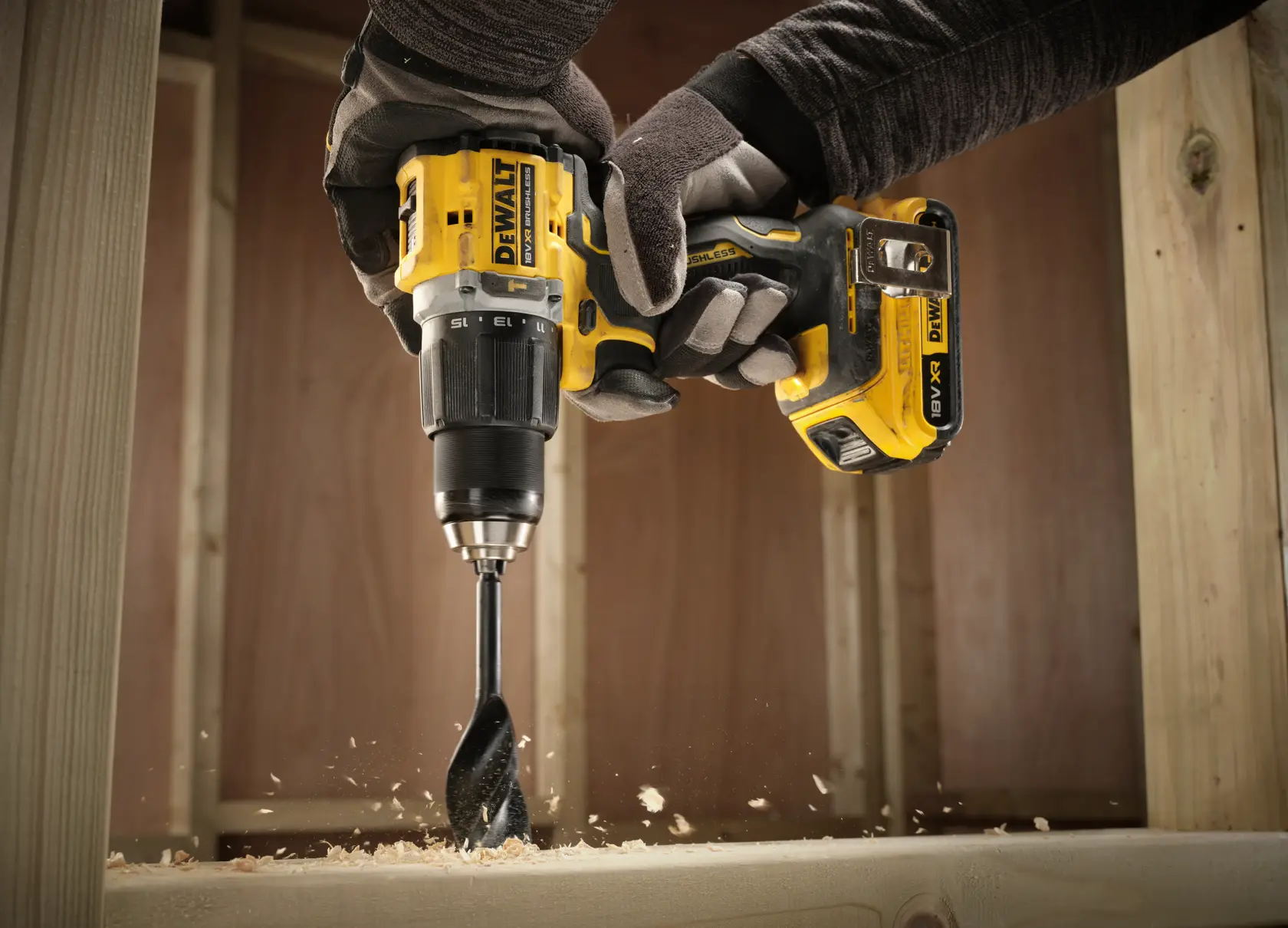 DEWALT cordless drill in use, drilling into wood with wood shavings, operator wearing gloves.