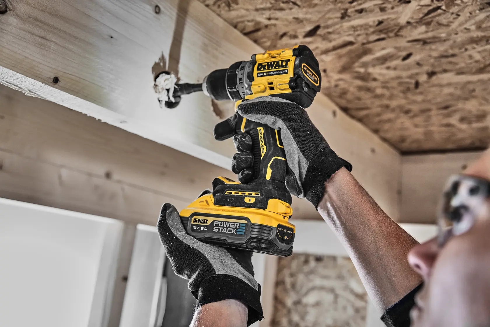 Person uses DEWALT cordless drill to drill into wood beam. The drill features POWERSTACK battery.