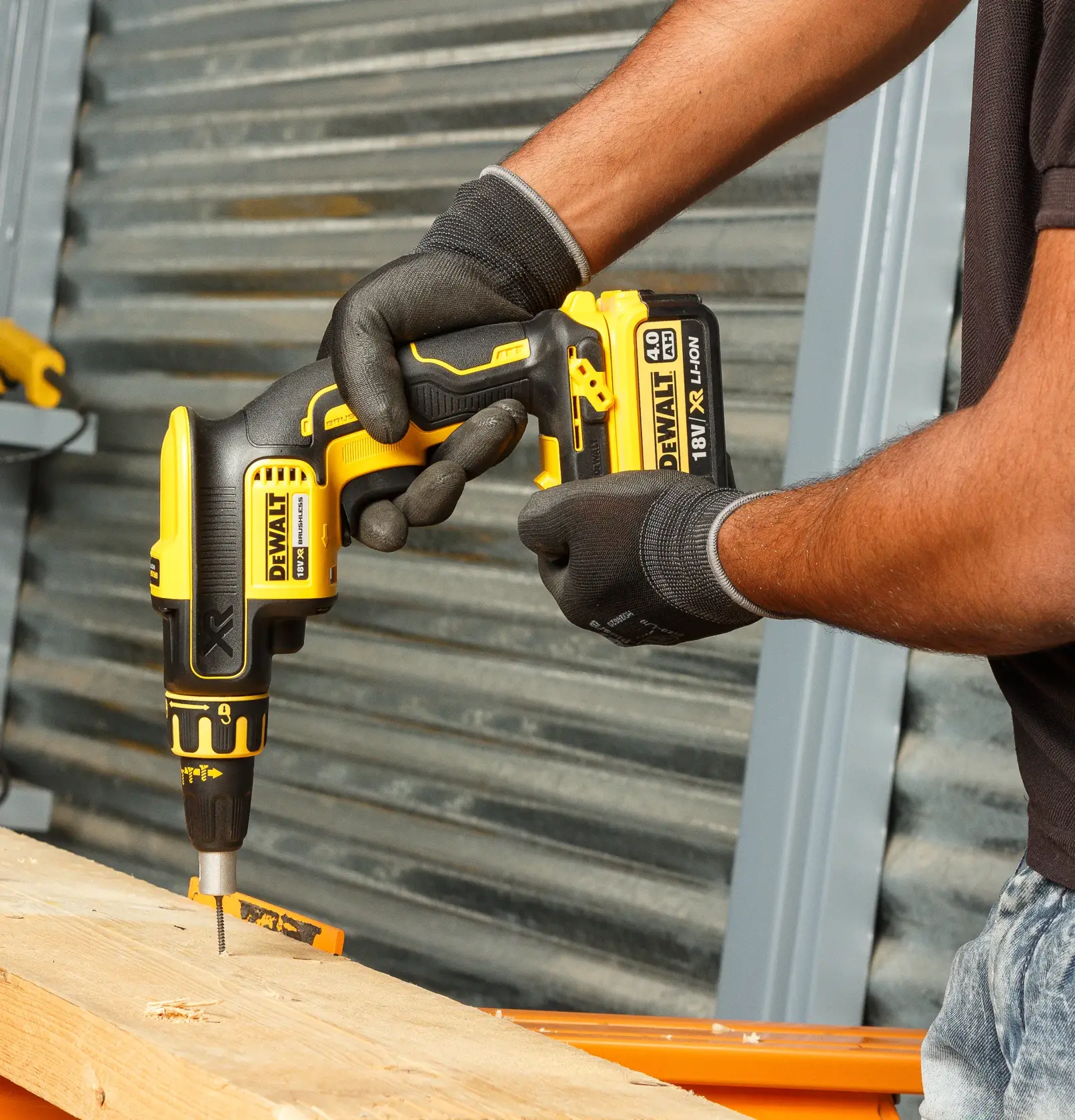 Person uses DEWALT DCF620NT-XJ cordless screwdriver to drill into wood, wearing gloves for protection.
