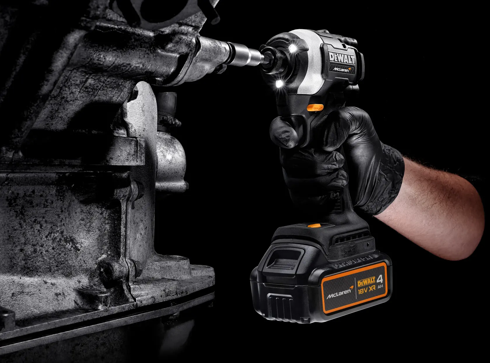 A person uses a DEWALT cordless impact driver to tighten a bolt on a metal machine part, wearing a black glove.