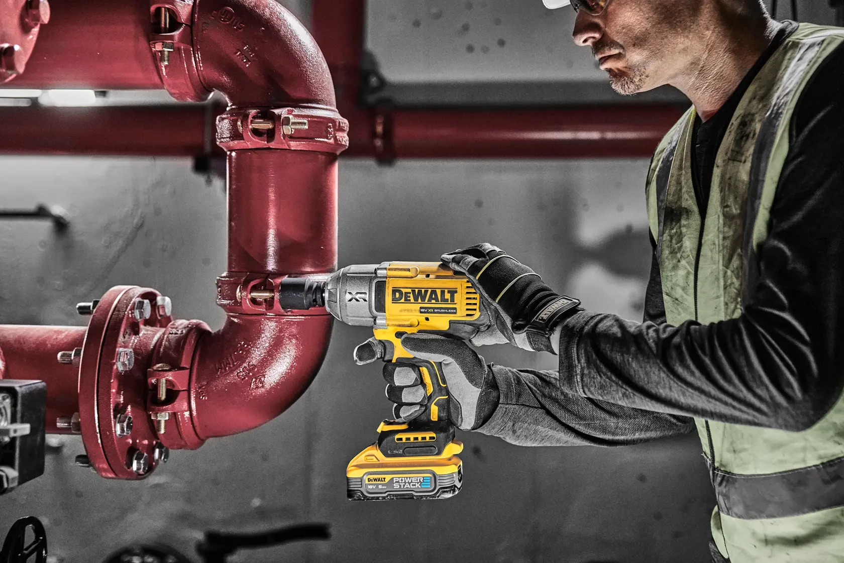 Worker uses DEWALT cordless impact wrench on a concrete structure at a construction site.