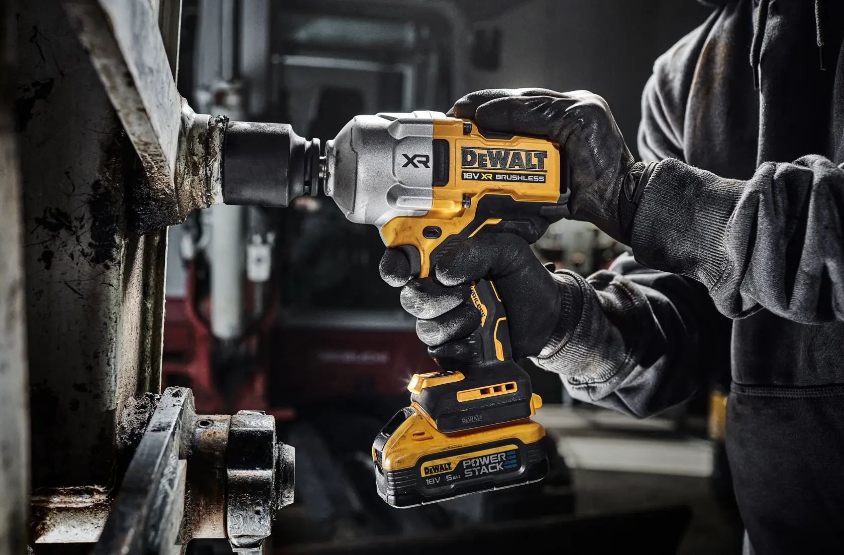 DEWALT cordless impact wrench in use by gloved hands on metal machinery in an industrial workshop.