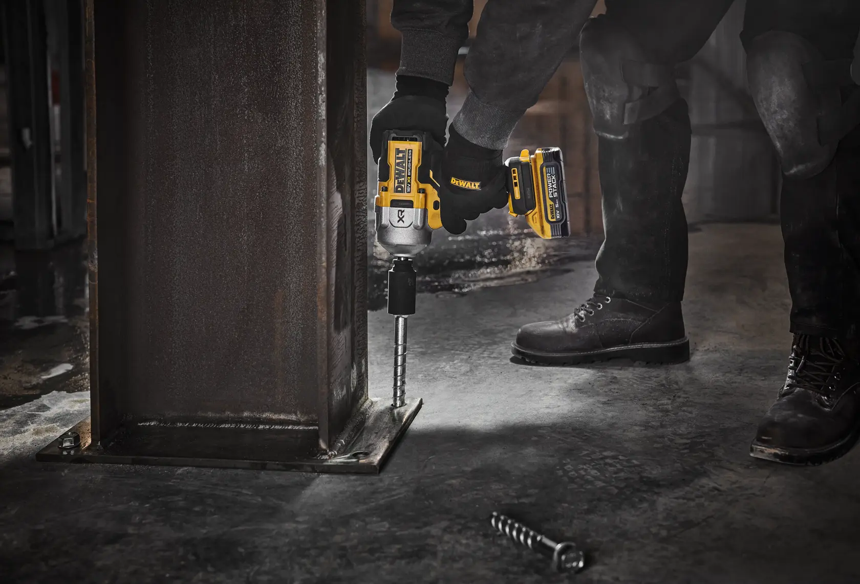 Person uses DEWALT cordless impact wrench DCF961H2T to fasten bolt to steel column on industrial site.