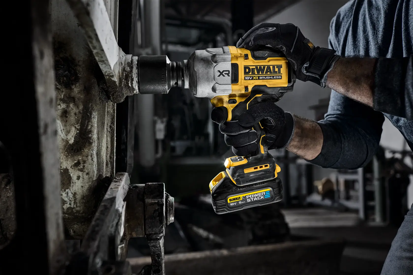 Hand using DEWALT cordless impact wrench on metal machinery in workshop setting.