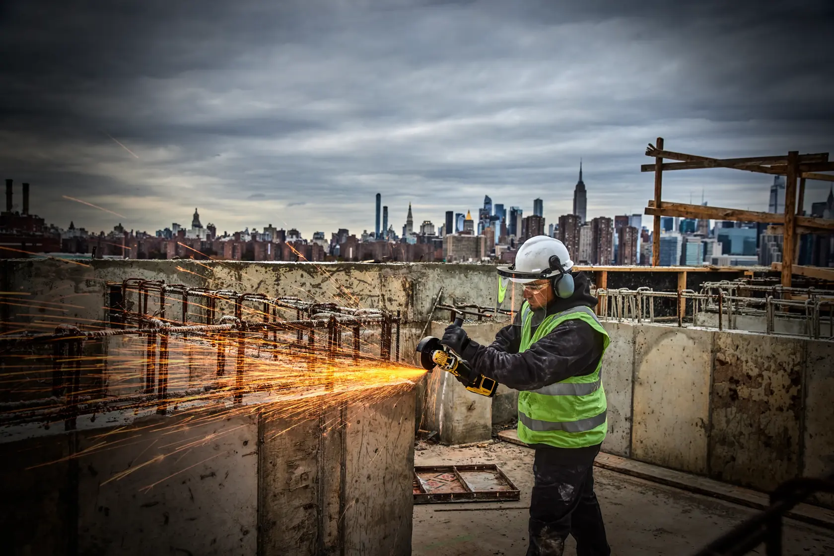 Person using a DEWALT cordless angle grinder on a concrete block, producing dust indoors.