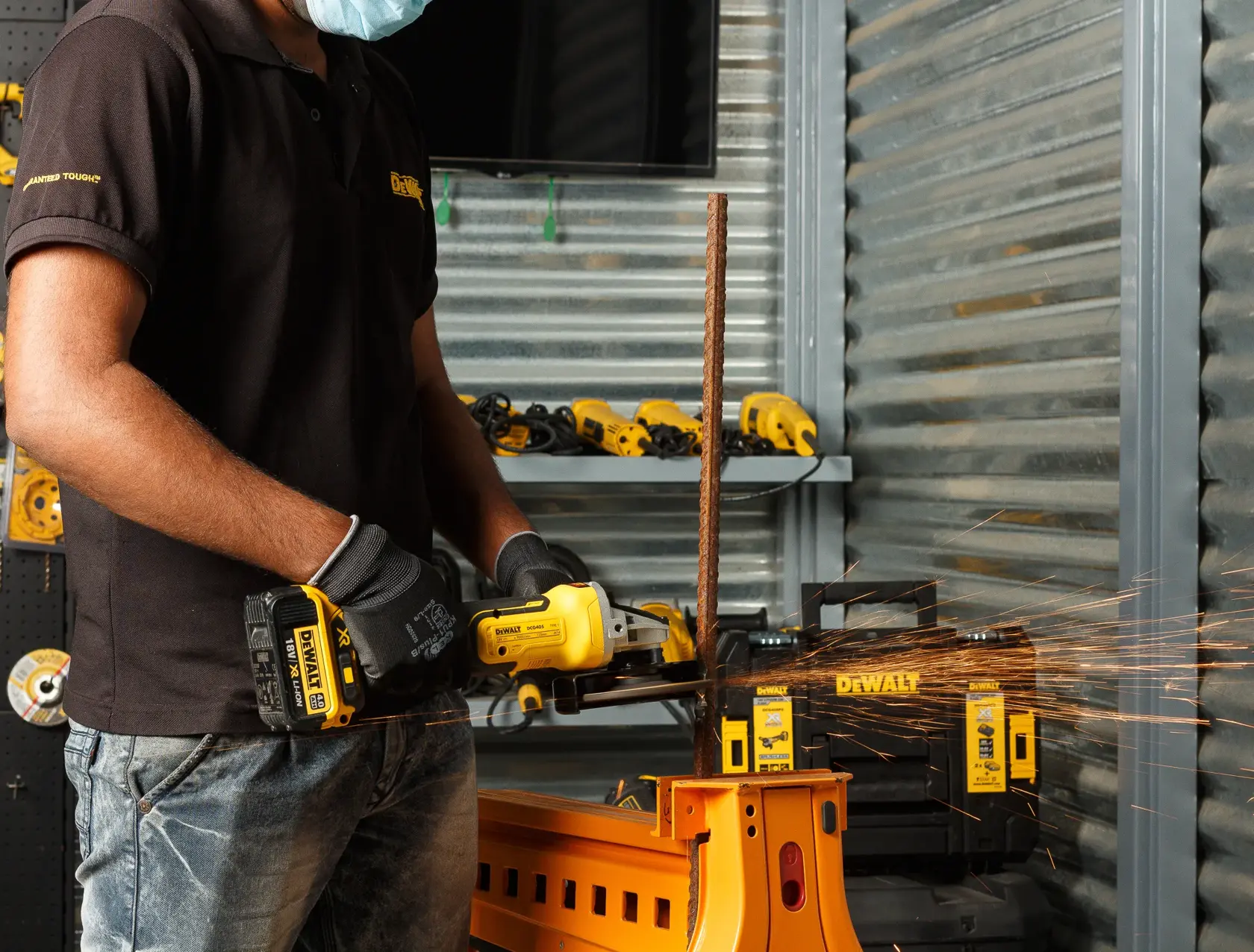Person uses a DEWALT cordless grinder to cut metal, with sparks visible in a workshop setting.