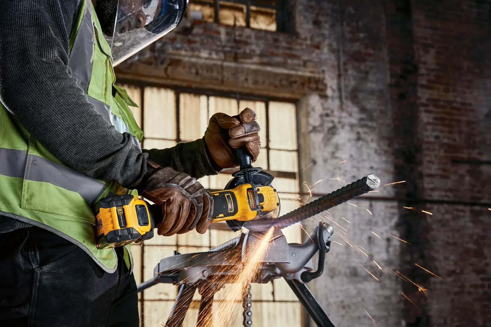 A DEWALT cordless grinder cutting metal, with sparks flying, operated by a worker in safety gear.