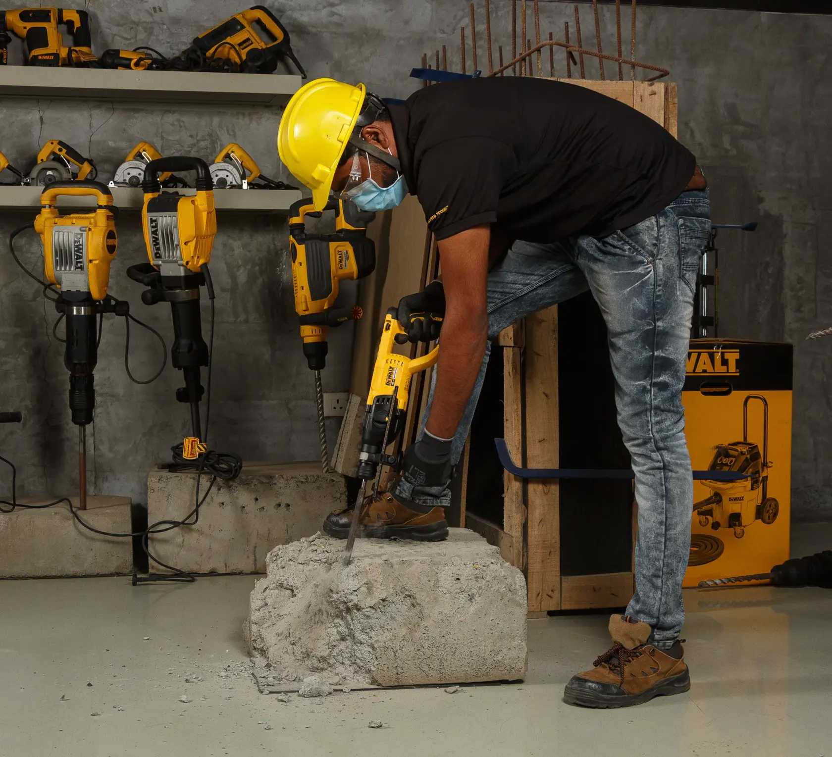Ouvrier perce du béton avec une perceuse DEWALT, équipé de protections. D'autres outils DEWALT sont visibles.