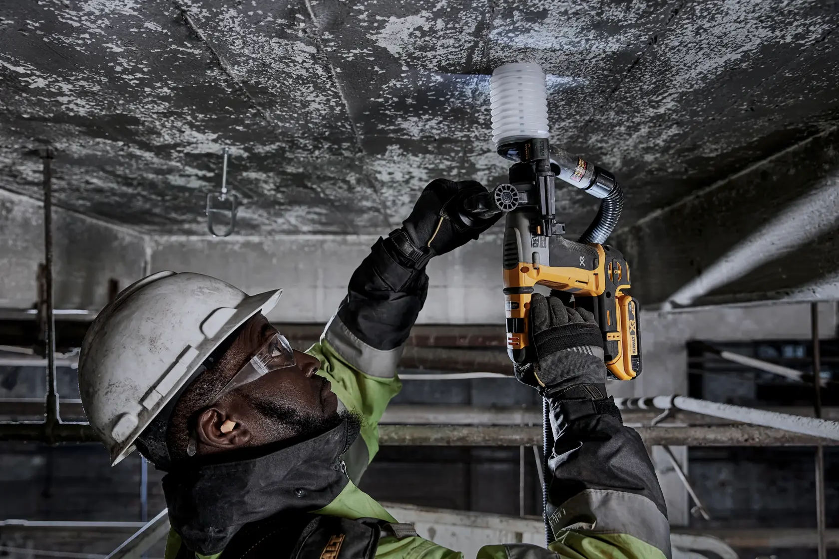Worker uses DEWALT DCH172NT-XJ, DCH172NT on ceiling. Industrial setting, safety gear worn.