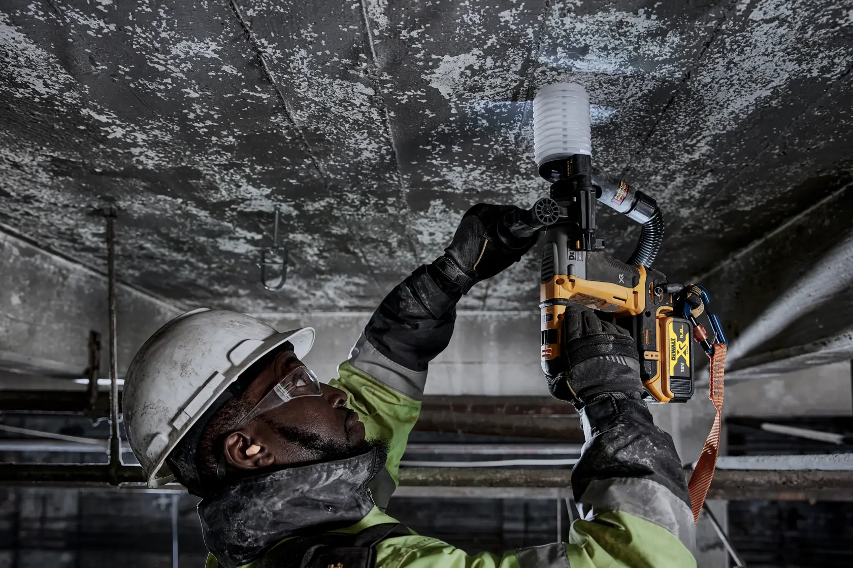 Operaio usa martello DEWALT DCH172P2 sul soffitto, con dispositivi di sicurezza in ambiente industriale.