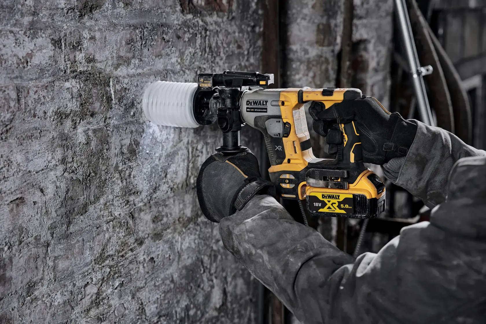 Persona usa un martello rotante DEWALT a batteria per perforare un muro di cemento sul cantiere.