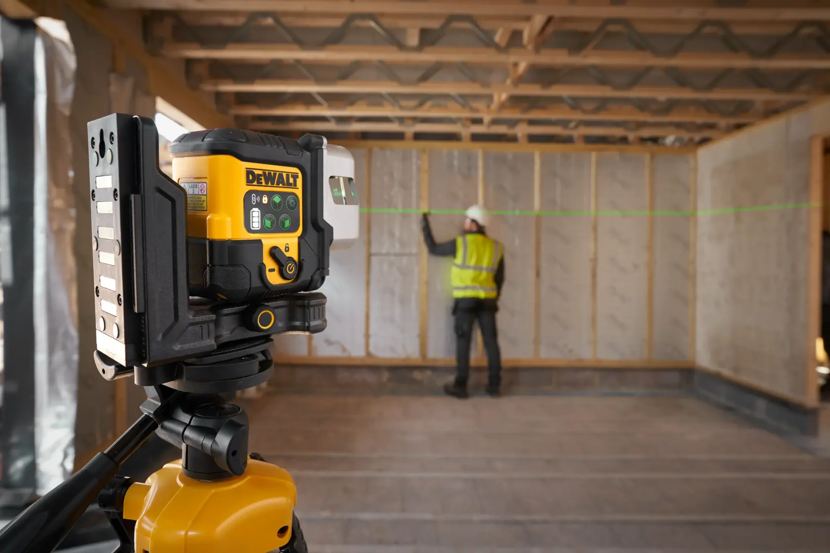 Operaio usa livello laser DEWALT verde per allineare in un edificio in costruzione.