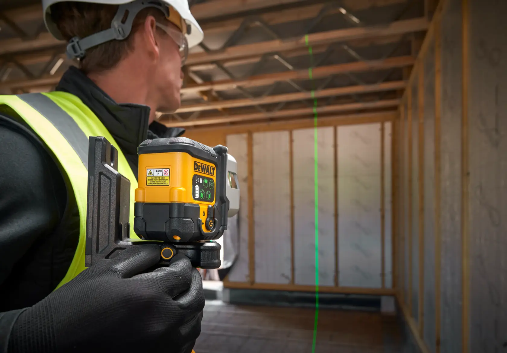 Livella laser DEWALT su treppiede proietta una linea verde in una stanza con mobili installati.