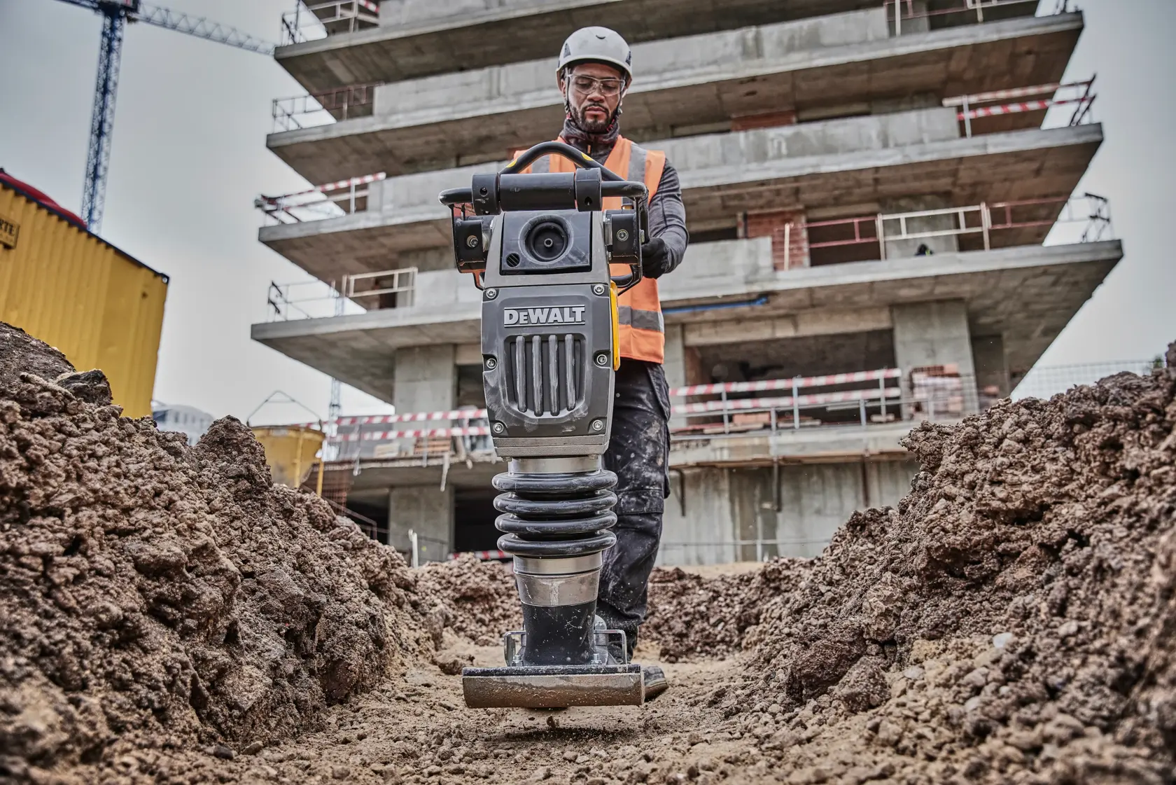 DEWALT compactor in use on a construction site, operated by a worker in safety gear.