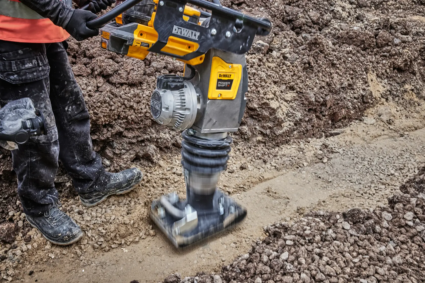 DEWALT compactor is being used on soil at a construction site by a worker wearing protective gear.