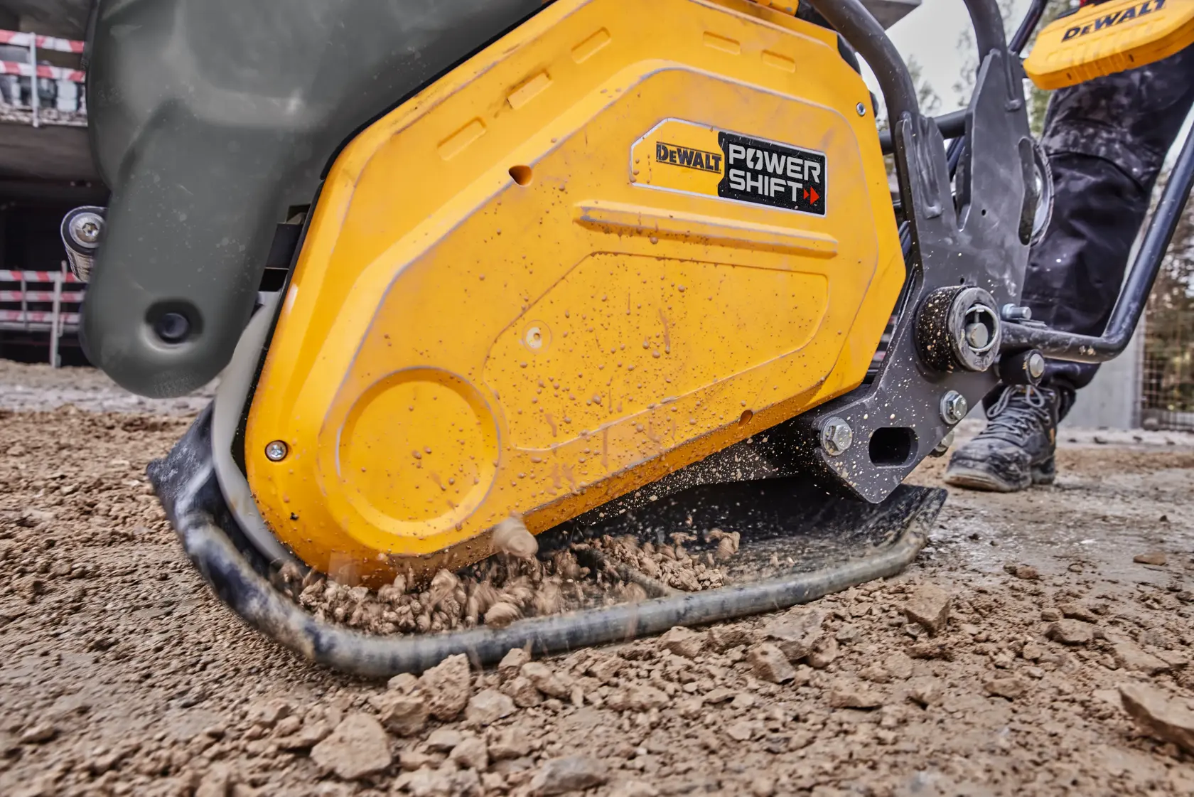 DEWALT POWER SHIFT compactor working on soil at a construction site, close-up of yellow machine in use.