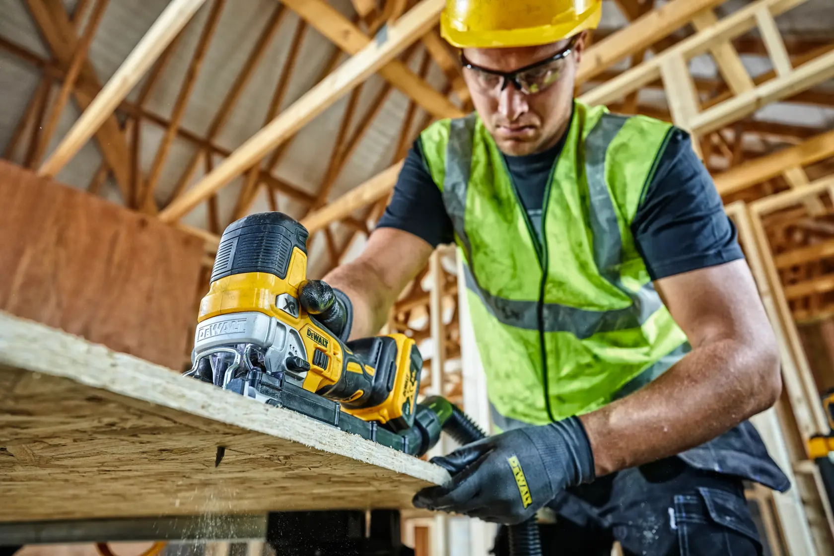 Worker uses DEWALT cordless jigsaw to cut wood in a construction site. Tool model DCS335P2 visible.