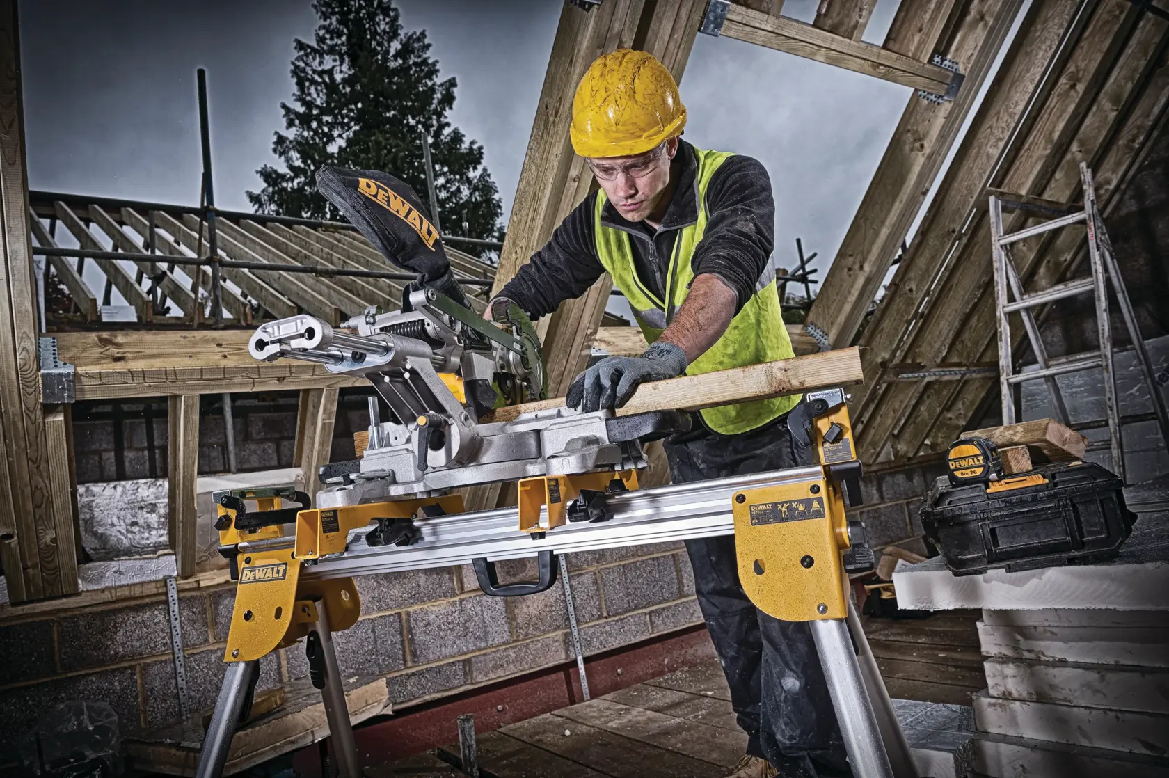 Worker uses DEWALT DCS365N saw to cut wood on a construction site with timber framing, safety gear worn.
