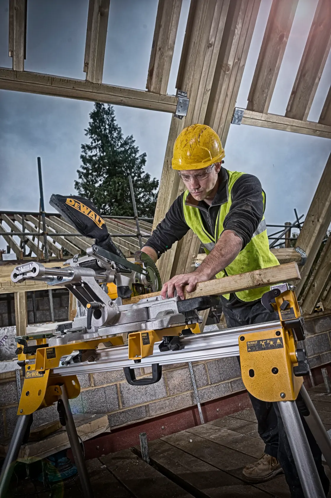 Worker uses DEWALT DCS365N saw to cut wood at a construction site with unfinished timber framing.