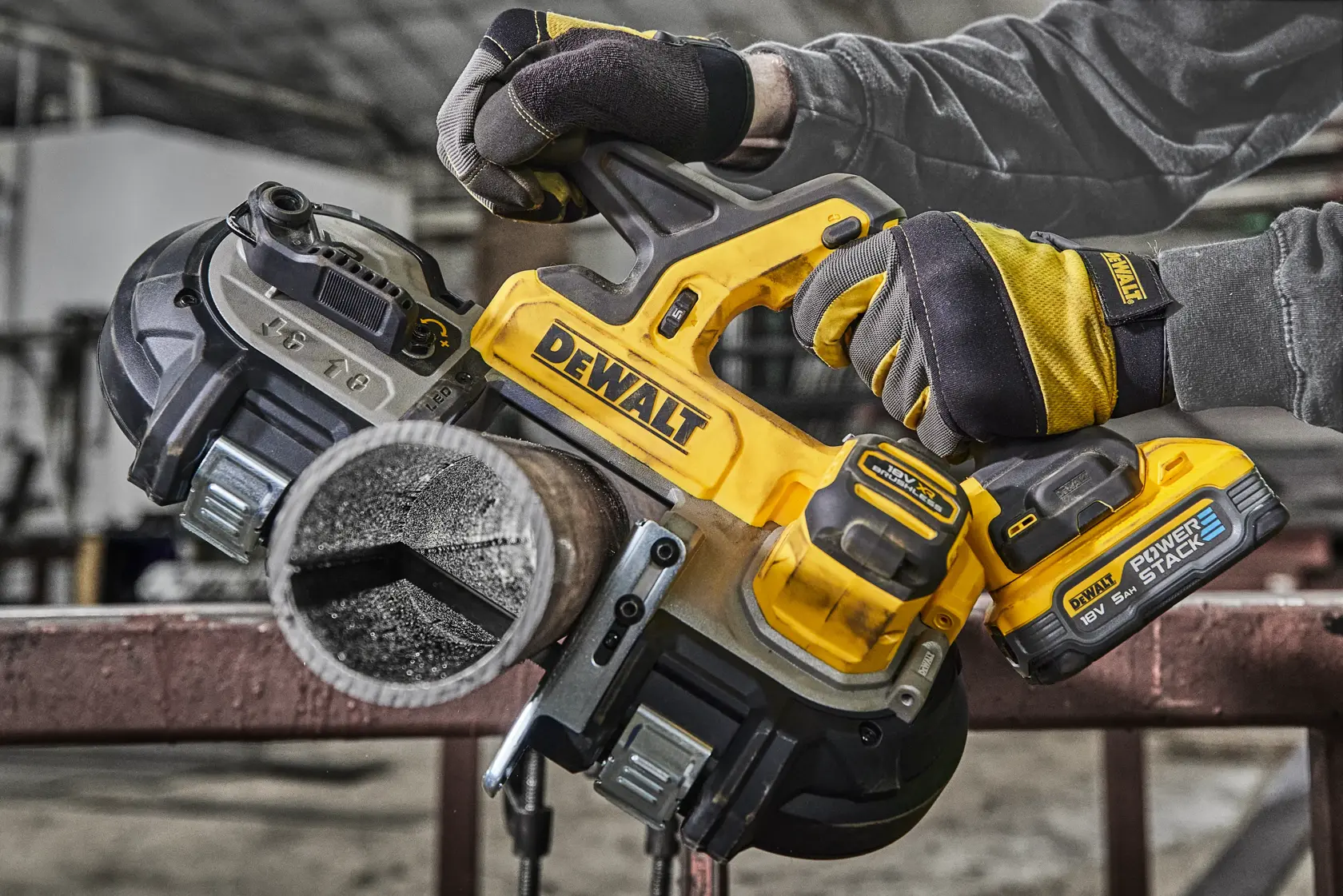 DEWALT cordless band saw cutting a metal pipe, held by gloved hands in an industrial workshop setting.