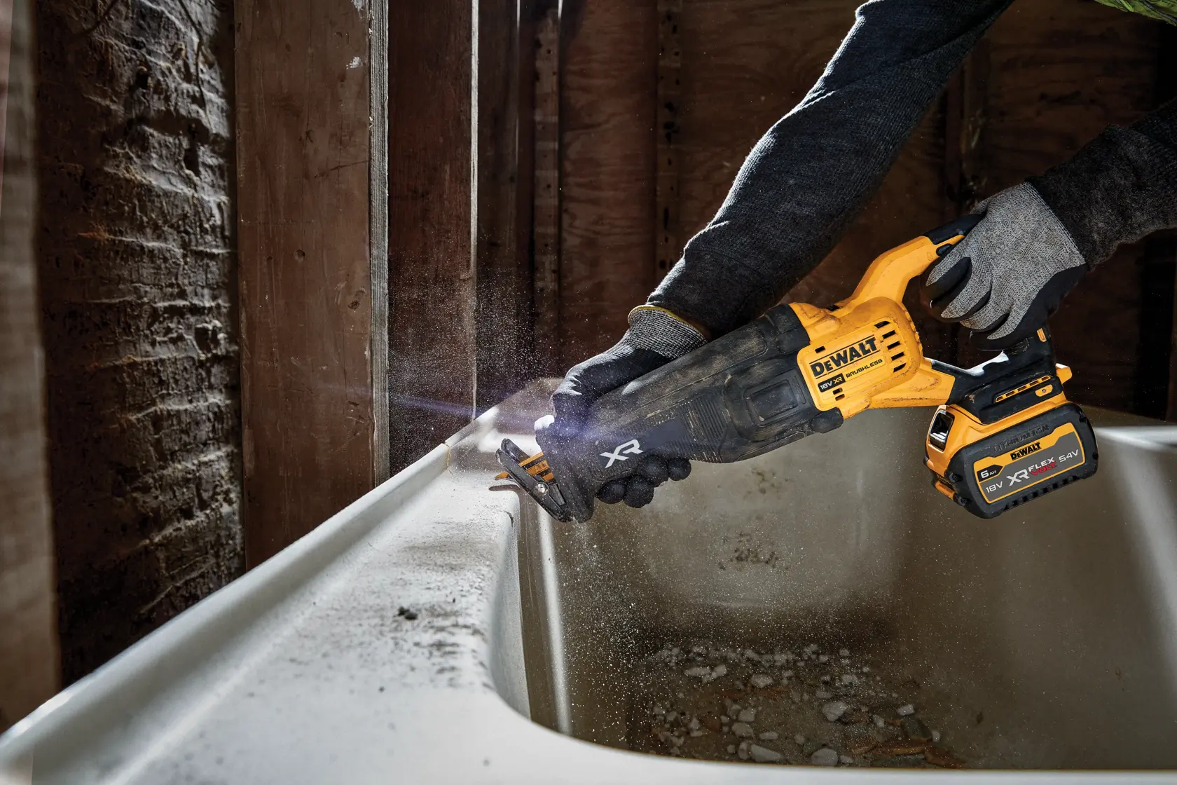 Person uses DEWALT cordless reciprocating saw to cut material near a bathtub during renovation.