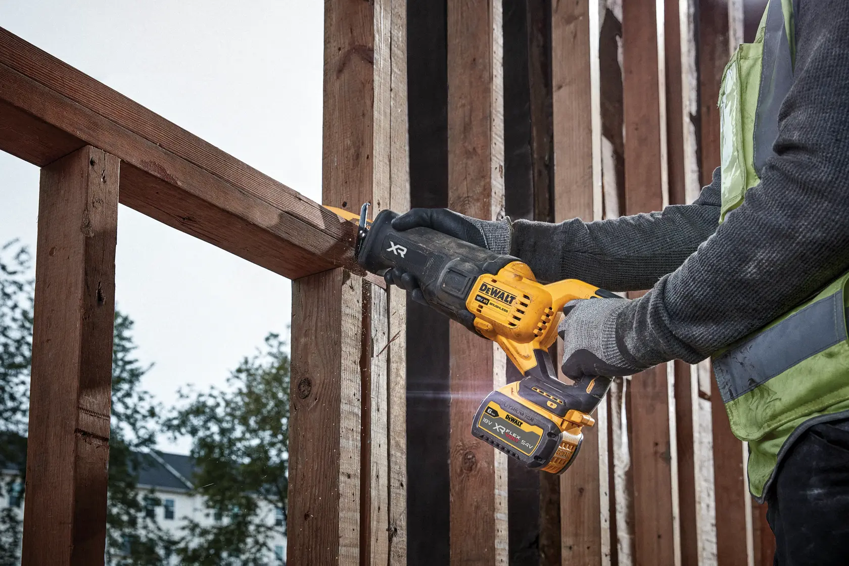 Person uses a DEWALT DCS386NT reciprocating saw to cut a wooden beam at a construction site.