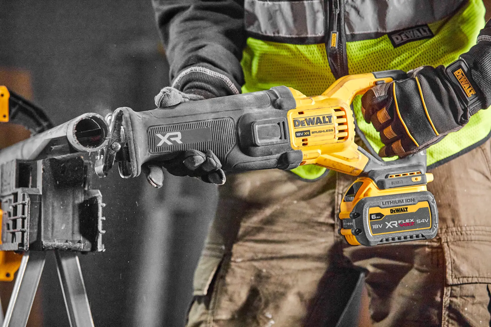 A DEWALT XR cordless reciprocating saw is being used to cut through a pipe in a workshop setting.