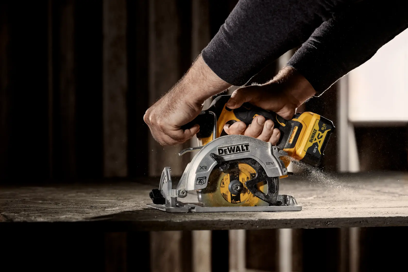 Hands using a DEWALT cordless circular saw to cut wood, with sawdust flying during operation.