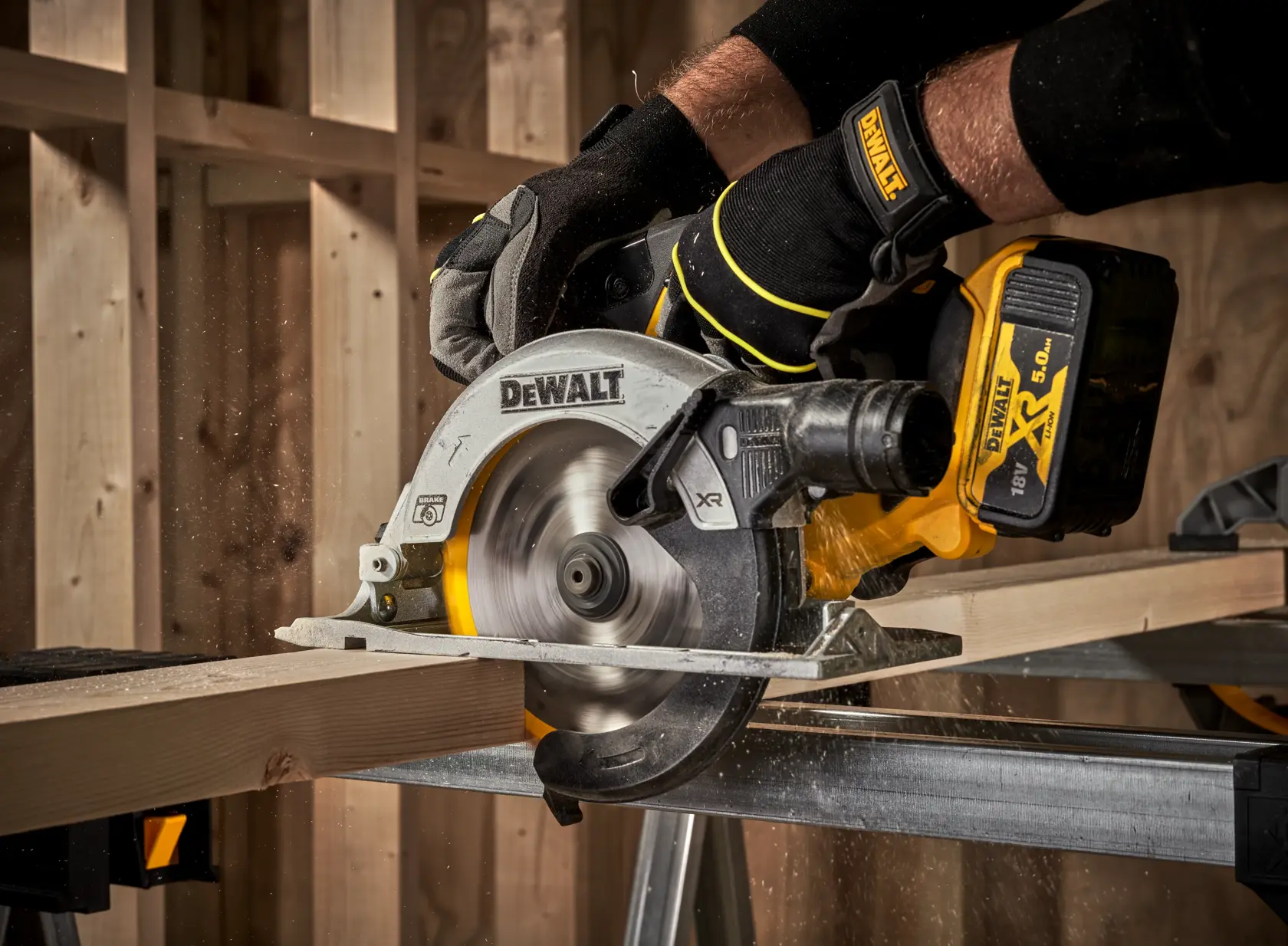 DEWALT cordless circular saw cutting wood, held by gloved hands in a workshop.