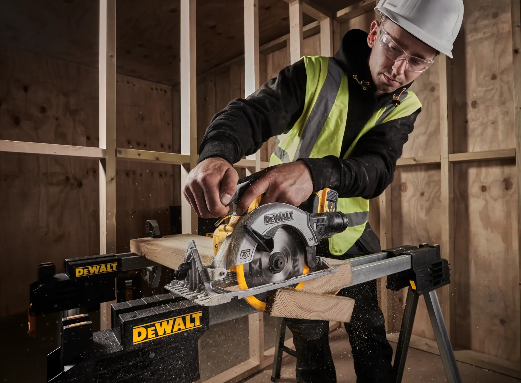 Person using a DEWALT circular saw to cut wood on a worksite, wearing safety gear and high-visibility vest.