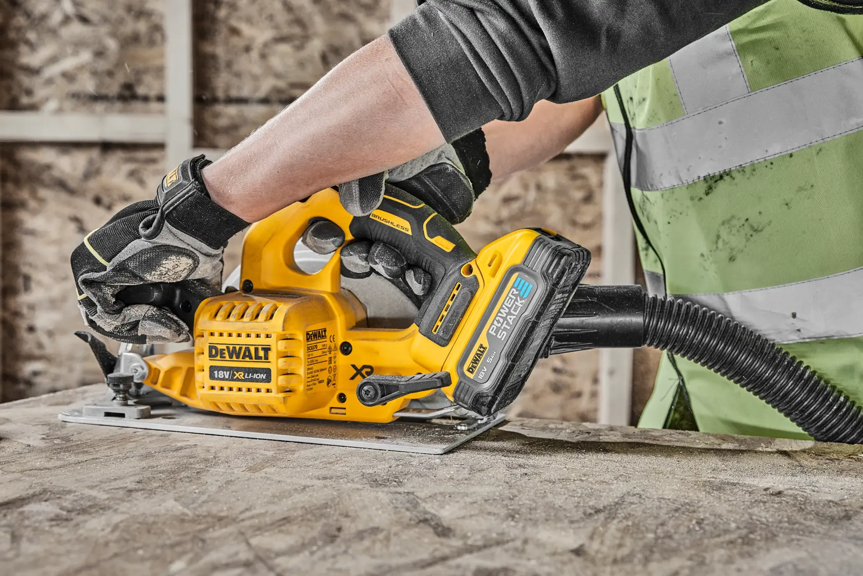 Worker uses DEWALT circular saw to cut wood at construction site, wearing safety gear and gloves.