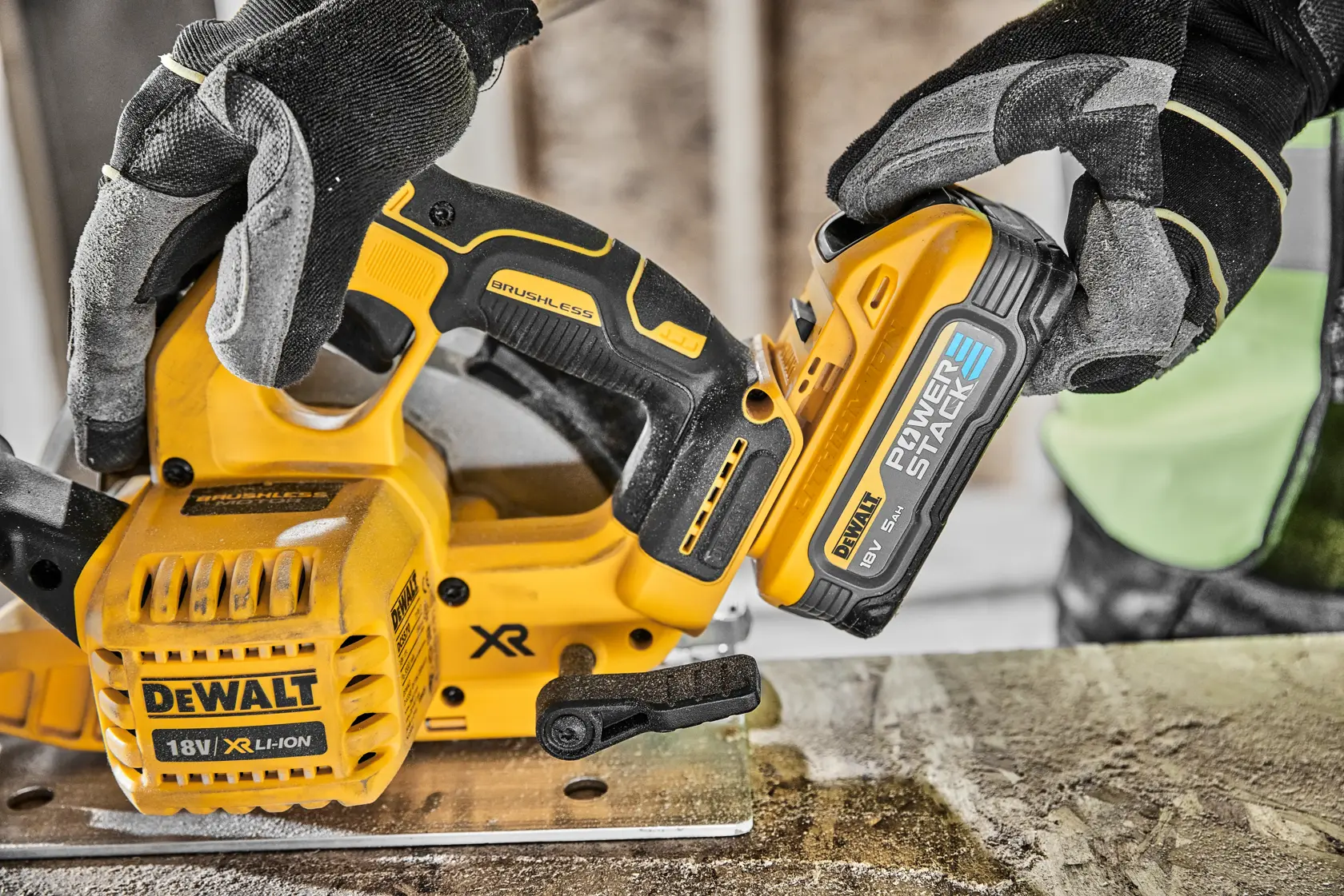 Gloved hands using a DEWALT cordless circular saw to cut wood, with a vacuum attachment.