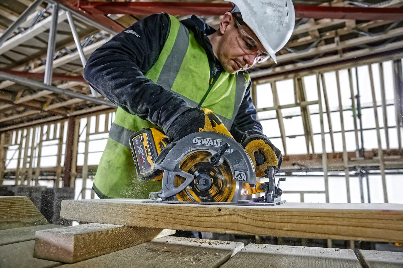 Worker using DEWALT DCS578NT circular saw to cut wood at a construction site.