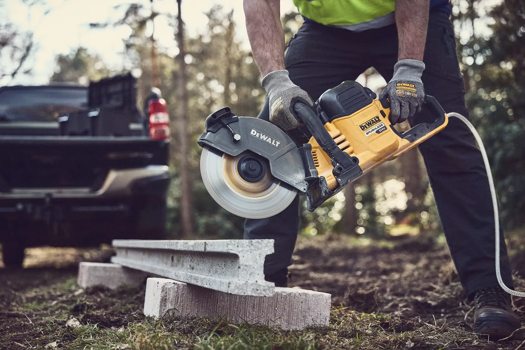 Sega DEWALT taglia il cemento all'aperto, operatore con guanti protettivi.