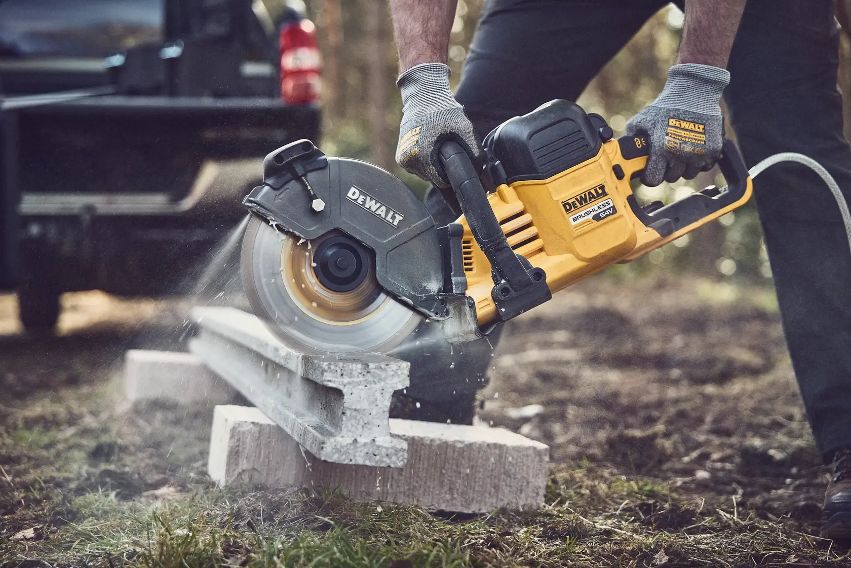 A DEWALT cordless brushless cut-off saw kit with a 230mm disc, shown with two 18V/54V XR FlexVolt batteries and a yellow battery charger.