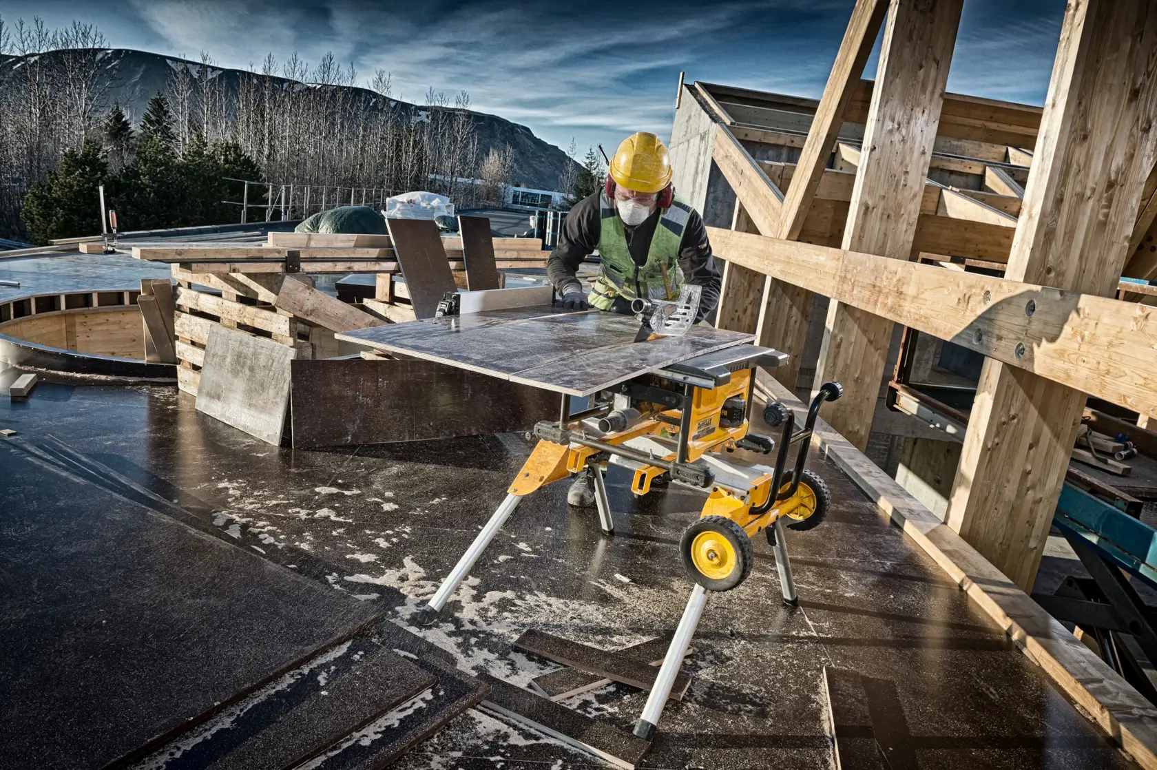 DEWALT DCS7485N table saw in use at a construction site, worker wearing safety gear cutting wood panels.