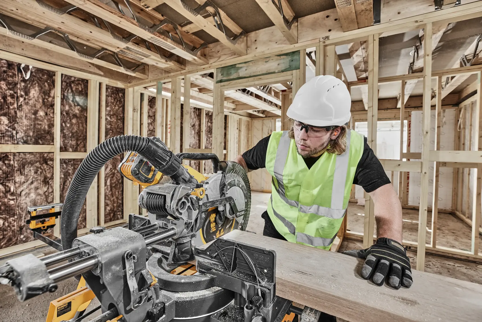 DEWALT DCS781X2-QW, DCS781X2 saw in use on site. Worker in safety gear cutting wood, construction background.