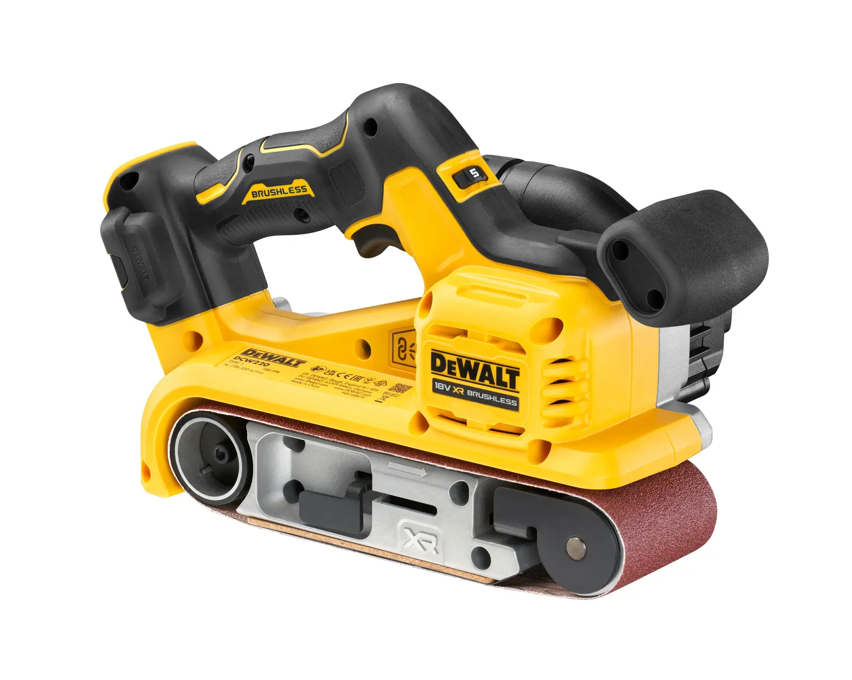 En person i et verksted bruker en gul DEWALT DCW220N båndsliper på en treplanke. Personens ansikt er uskarpt. Omgivelsene viser trepaneler og ulike verktøy.