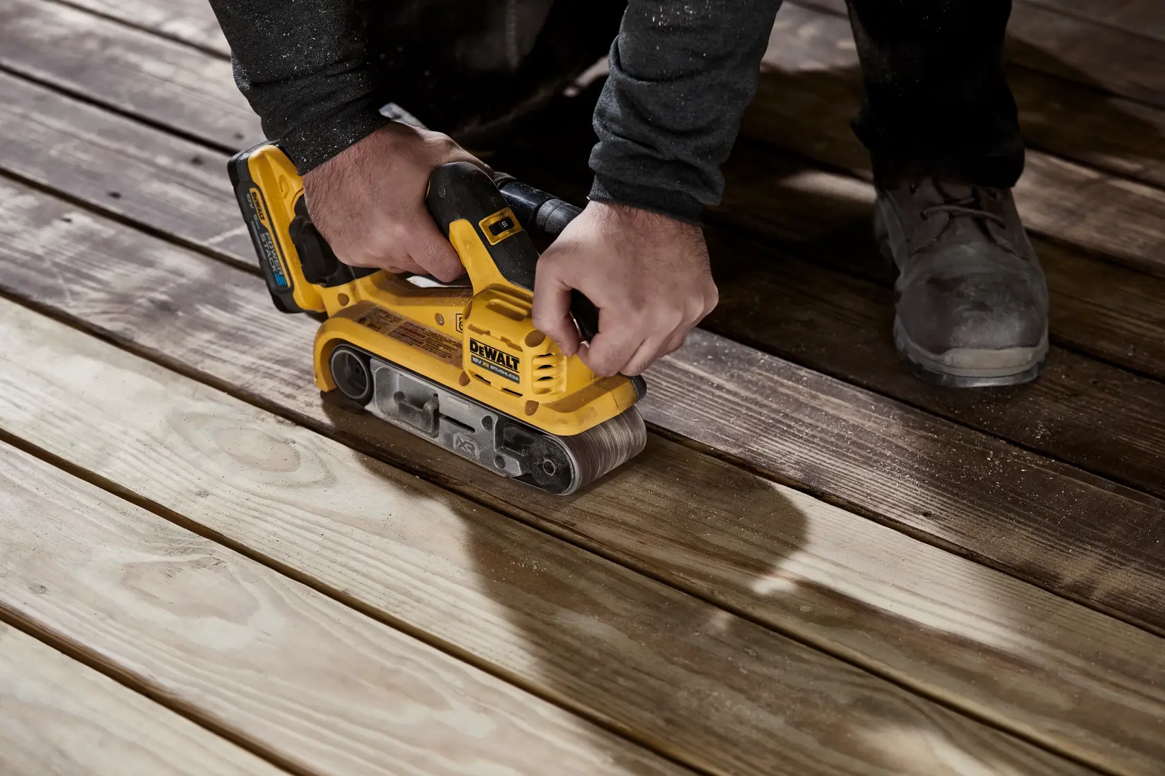 DEWALT cordless belt sander with yellow and black design, used for smoothing wood surfaces.
