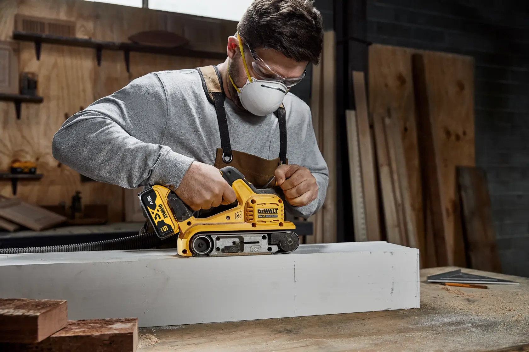 DEWALT cordless belt sander kit with batteries, charger, dust bag, and hard carrying case. All items shown together.