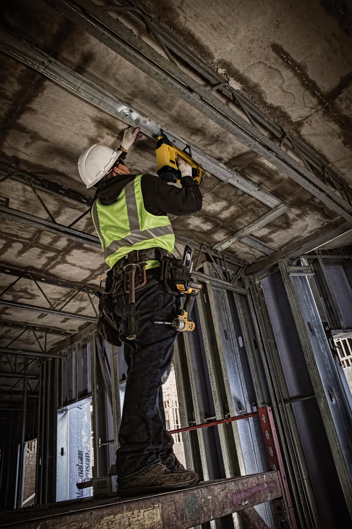 Worker uses DEWALT photography tool DGN845D1-QW, DGN845D1 at construction site. Safety gear is visible.