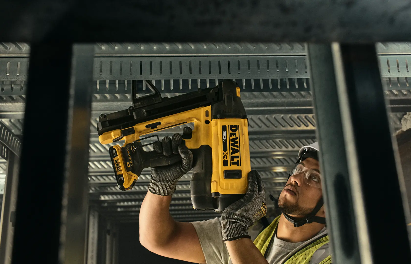 Worker uses DEWALT nailer DGN845D1-QW, DGN845D1 on metal ceiling. Photography category. Face blurred.