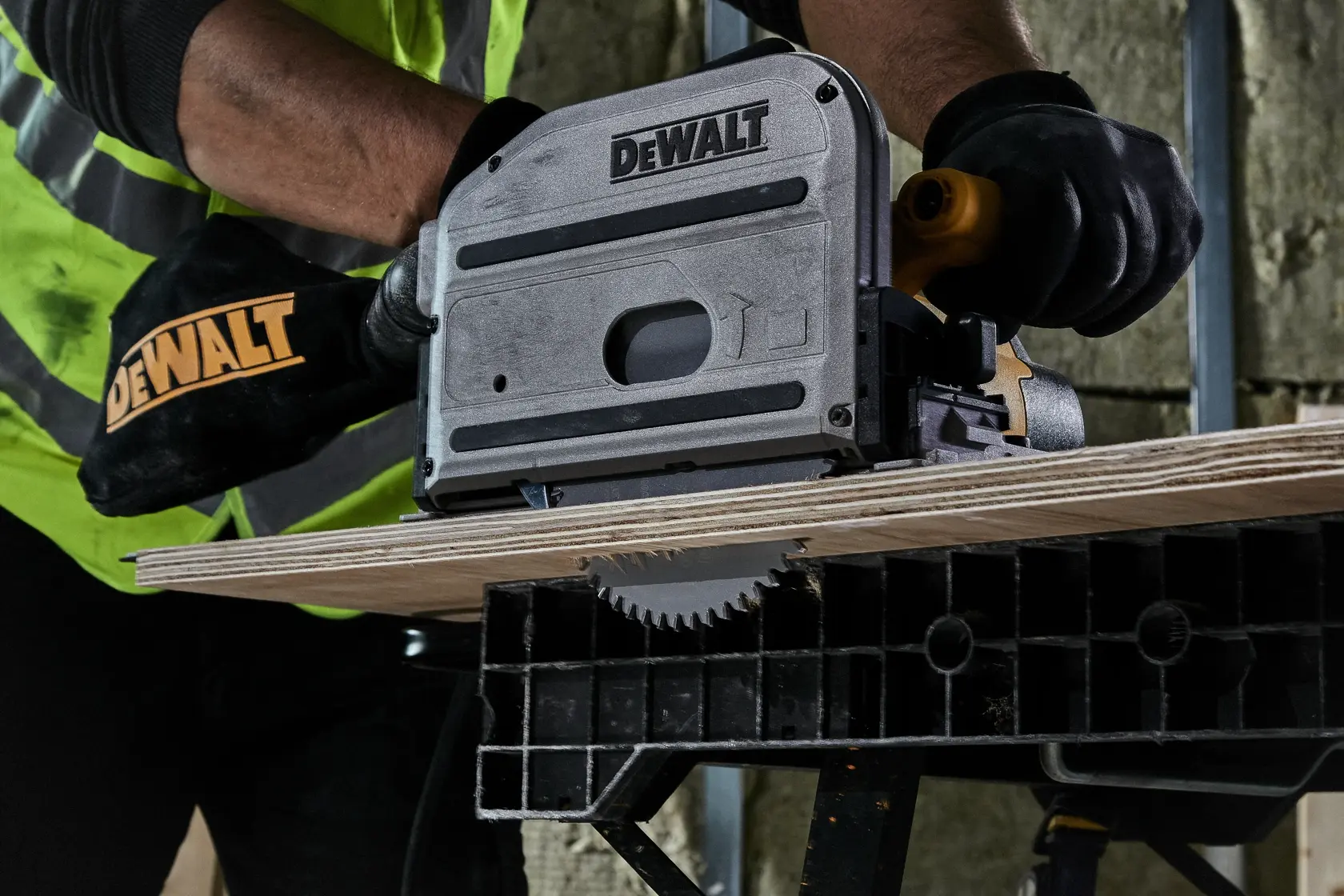 DEWALT circular saw is cutting plywood on a workbench, operated by a worker with gloves and safety vest.