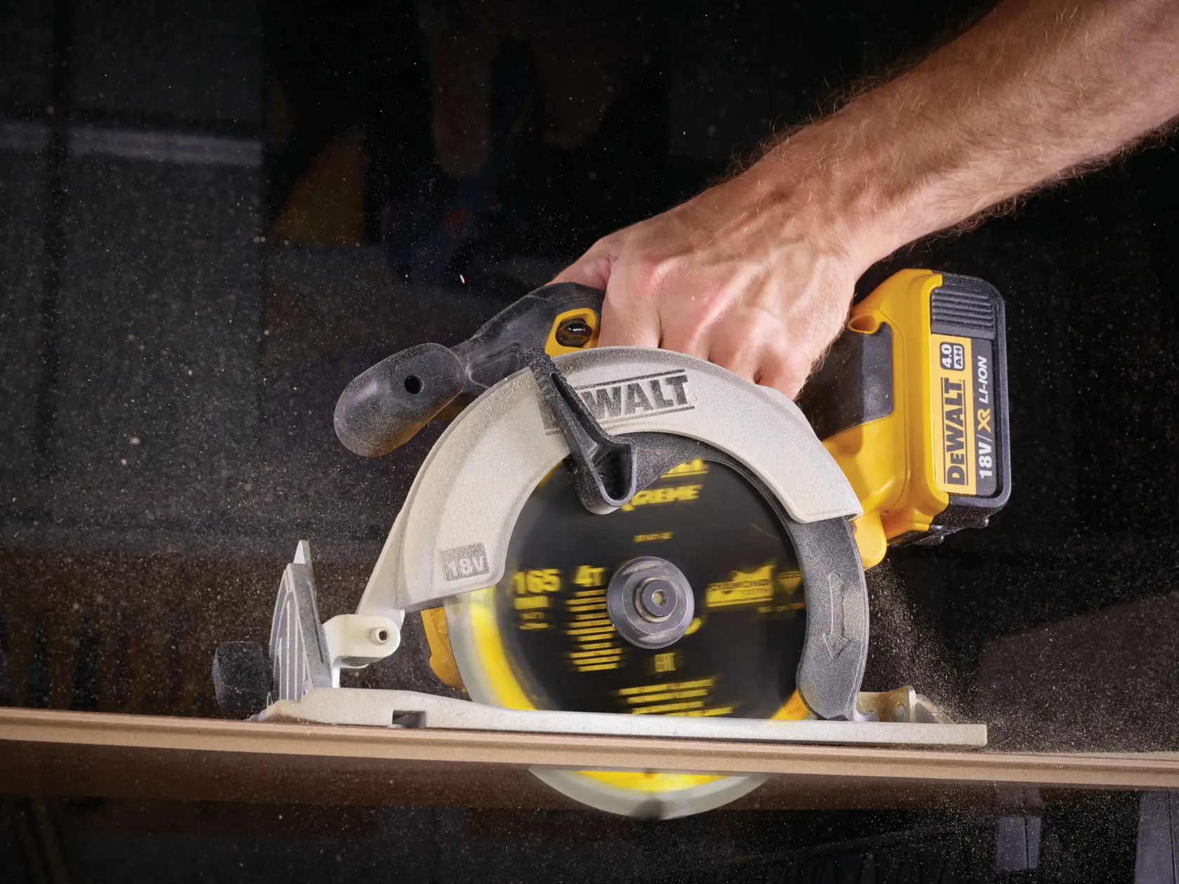 Sega circolare DEWALT senza fili taglia il legno, tenuta da una persona, con trucioli volanti.